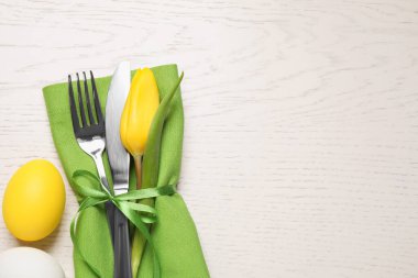 Çatal bıçak seti ve yumurtalar beyaz ahşap masaya, düzlük ve yazı için yer vardı. Paskalya kutlaması