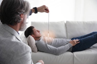 Ofiste hipnoterapi seansı sırasında sarkacı kullanan psikoterapist.