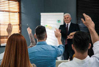 Seminerde insanlar soru sormak için ellerini kaldırıyorlar.