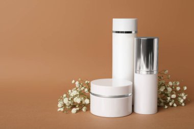 Kahverengi arka planda lüks kozmetik ürünleri ve çiçekler. Metin için boşluk