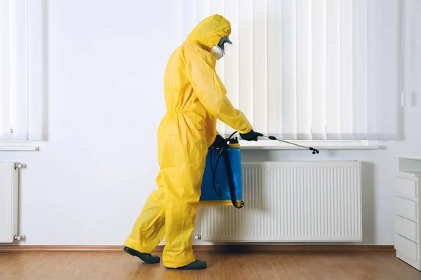 穿着防护服在室内喷洒杀虫剂的虫害防治工作者 — 图库照片