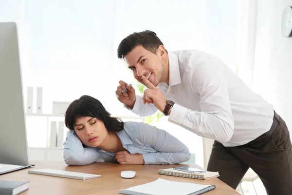 Man drawing on colleague\'s face while she sleeping at workplace. April fool\'s day