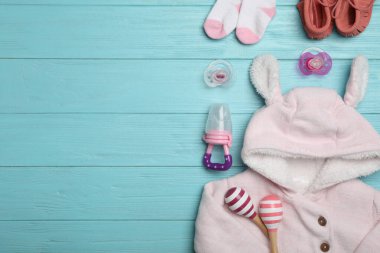 Açık mavi ahşap masa üzerinde çocuk giysileri ile düz kompozisyon, metin için boşluk