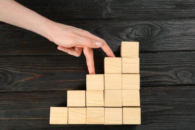 Kadın ve merdivenler siyah ahşap arka planda küplerle yapılmış, üst manzara. Kariyer tanıtımı konsepti