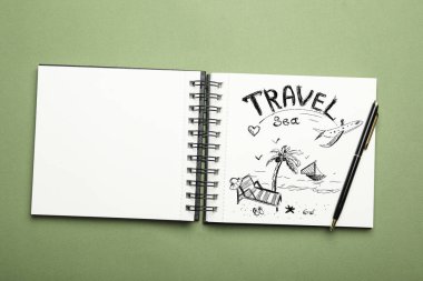 Yeşil arkaplan üzerinde açık defter ve kalem, üst görünüm