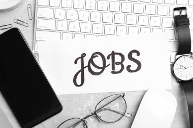 Açık gri mermer masa üzerinde JoBS kelimesi, bilgisayar klavyesi ve akıllı telefondan oluşan düz kompozisyon. Kariyer konsepti