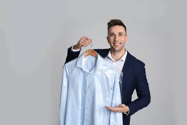 Hombre Sosteniendo Percha Con Camisa Bolsa Plástico Sobre Fondo Gris —  Fotos de Stock