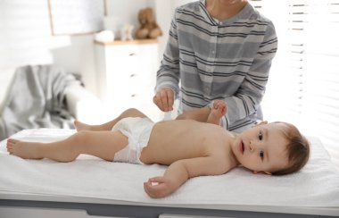 Anne evde bebek bezi değiştiriyor.