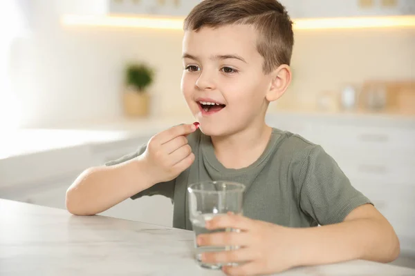 Liten Pojke Med Glas Vatten Tar Vitaminkapsel Köket — Stockfoto