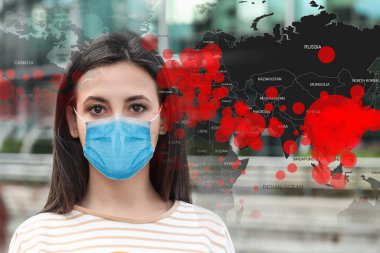 Coronavirus salgını sırasında tıbbi maskeli bir gazeteci haber sunuyor. Hastalığın yayıldığını gösteren dünya haritası