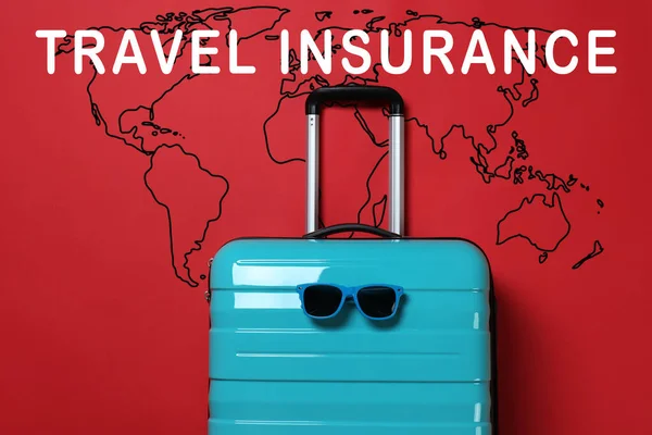 Niebieska Walizka Okularami Przeciwsłonecznymi Frazą Travel Insurance Czerwonym Tle — Zdjęcie stockowe