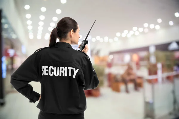 Security guard using portable radio transmitter in shopping mall, space for text