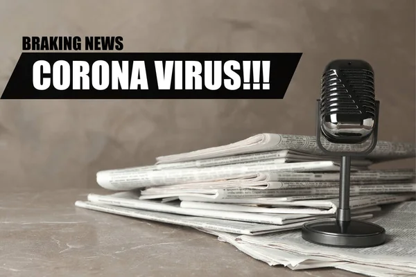 Phrase Corona Virus, newspapers and vintage microphone on marble table. Journalist's work