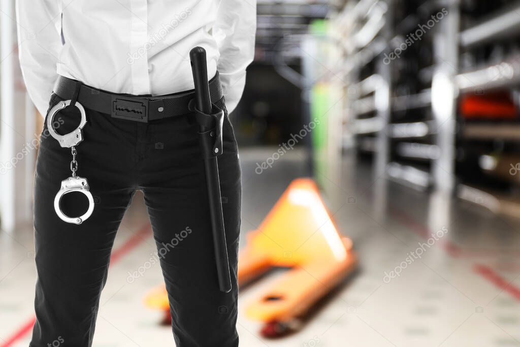 Security guard with handcuffs in wholesale warehouse, closeup. Space for text