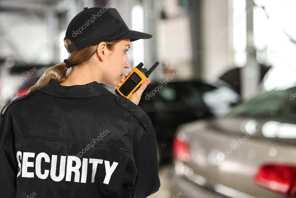 Security guard using portable radio transmitter in automobile repair shop, space for text