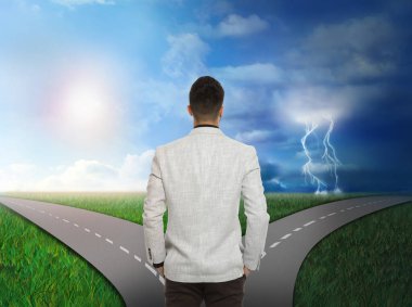 Kavşaktaki adam güneşli ve fırtınalı yollar arasında seçim yapıyor.