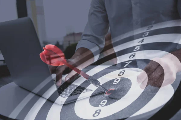 Businessman working with laptop and dart board. Double exposure