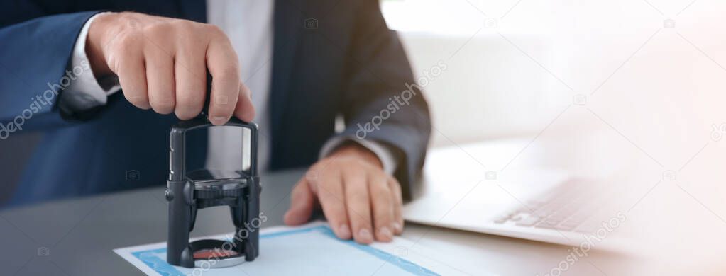 Male lawyer stamping document at desk in office, closeup. Banner design
