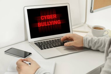 Genç adam beyaz masada dizüstü bilgisayar kullanıyor, yakın plan. Siber zorbalık