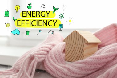 Enerji verimliliği kavramı. Kapalı alanda eşarba sarılı ahşap ev modeli.