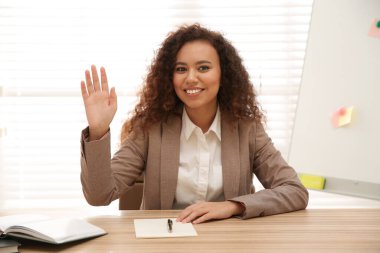 Happy African-American woman using video chat in office, view from web camera clipart