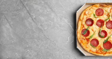 Açık gri mermer masada, karton kutuda nefis pepperoni pizza, üst manzara. Metin için boşluk