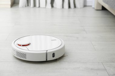 Modern robot elektrikli süpürgeyle yerleri süpürüyor. Metin için boşluk