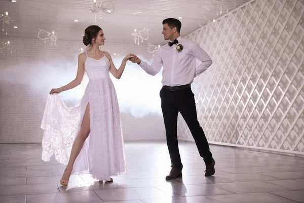 Happy newlywed couple dancing together in festive hall