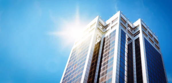 Modern skyscraper with tinted windows against blue sky, low angle view. Building corporation