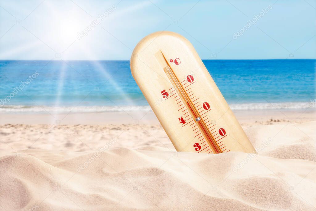Weather thermometer with high temperature on sandy beach near sea