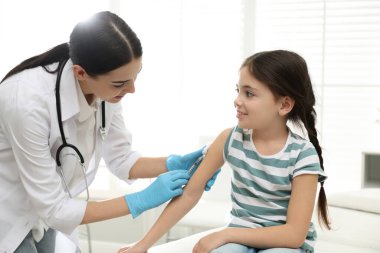 Modern klinikte küçük bir çocuğu aşılayan doktor.