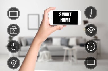 Akıllı evleri kontrol etmek için telefon uygulaması kullanan bir kadın.