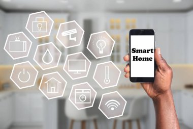 Akıllı evleri kontrol etmek için telefon uygulaması kullanan bir adam.