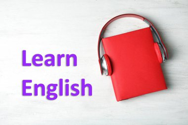 Ahşap arka plan, üst manzara, sert kapaklı kulaklıklar. İngilizce öğren.