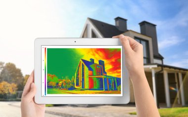 Evdeki ısı kaybını tespit eden bir kadın tablet ve açık havada termal izleyici kullanıyor. Enerji verimliliği