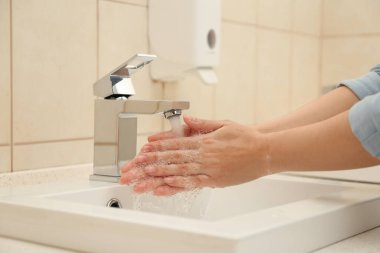 Banyoda ellerini antiseptik sabunla yıkayan bir kadın, yakın plan. Virüs önleme
