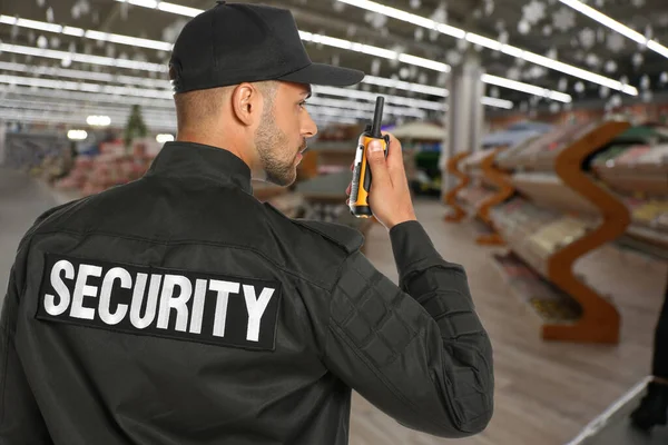 Security guard using portable radio transmitter in shopping mall