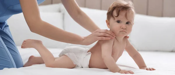 自宅の白いベッドの上で若い乳母とかわいい赤ちゃん バナーデザイン — ストック写真