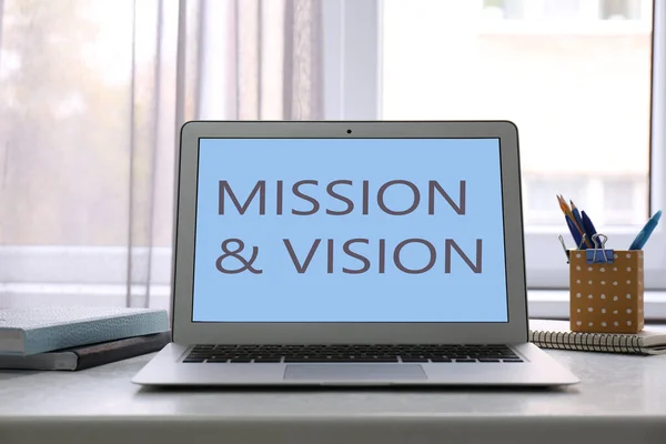 Modern laptop with phrase MISSION AND VISION on screen indoors