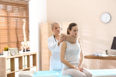 Klinikteki hastanın boynuna boyun tasması takan kadın ortopedist.