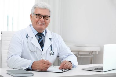 İş yerinde beyaz önlüklü kıdemli doktorun portresi.