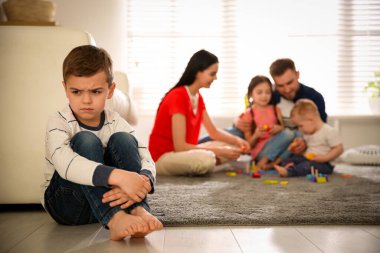 Mutsuz küçük çocuk, ebeveynler diğer çocuklarla evde vakit geçirirken kıskançlık hissediyor.