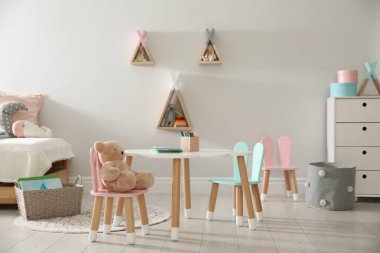 Küçük masa ve çocuk odasının içinde tavşan kulaklı sandalyeler.