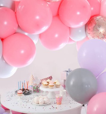 Kız için bebek partisi. Odadaki lezzetli ikramlar balonlarla süslenmiş.
