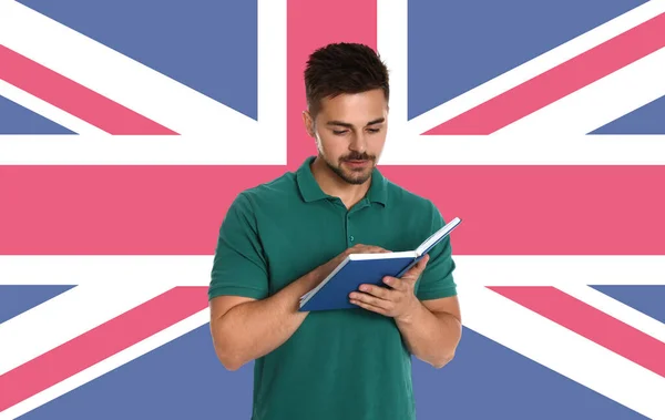 一个英俊的年轻人在墙上看书和英国国旗 学英语 — 图库照片