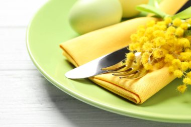 Beyaz ahşap arka planda çiçek desenli Paskalya sofrası, yakın plan.