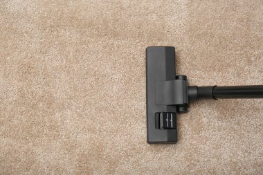 Kapalı alanda elektrikli süpürgeyle halıdaki toprağı temizlemek, üst manzara. Metin için boşluk