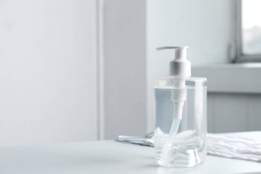 İçerideki masada antiseptik jel ve koruyucu maskeler, mesaj için yer. Virüsten koruma