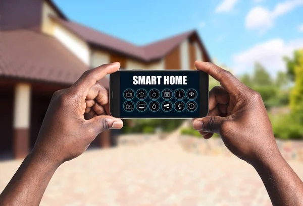 屋外でスマートホームを制御するための電話アプリケーションを使用して男 クローズアップ — ストック写真