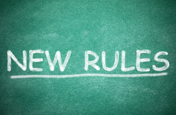 Text NEW RULES written on green board